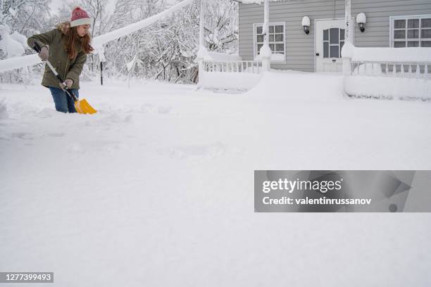 het meisje reinigt de sneeuw voor haar huis met een schop - thick girls stockfoto's en -beelden