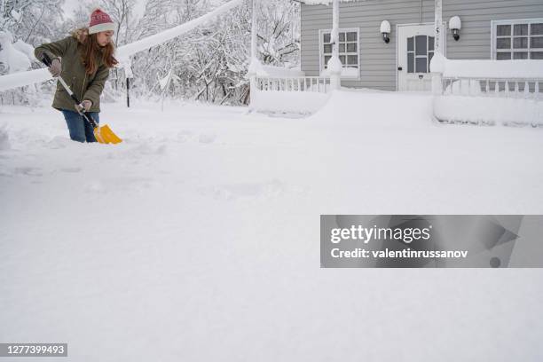 girl cleans the snow in front of her house with a shovel - deep snow stock pictures, royalty-free photos & images