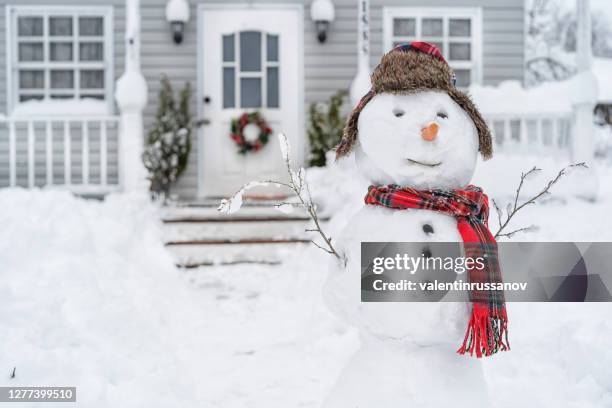 lächelnder schneemann vor dem haus am wintertag - snowman stock-fotos und bilder