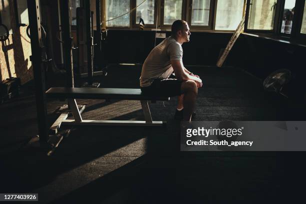 one athletic man resting on bench press in the gym - bench press stock pictures, royalty-free photos & images