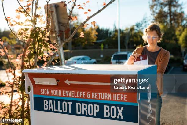 woman deposits absentee mail-in voters ballot - absentee ballot stock pictures, royalty-free photos & images