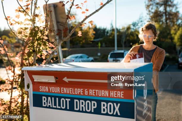 woman deposits absentee mail-in voters ballot - election box stock pictures, royalty-free photos & images