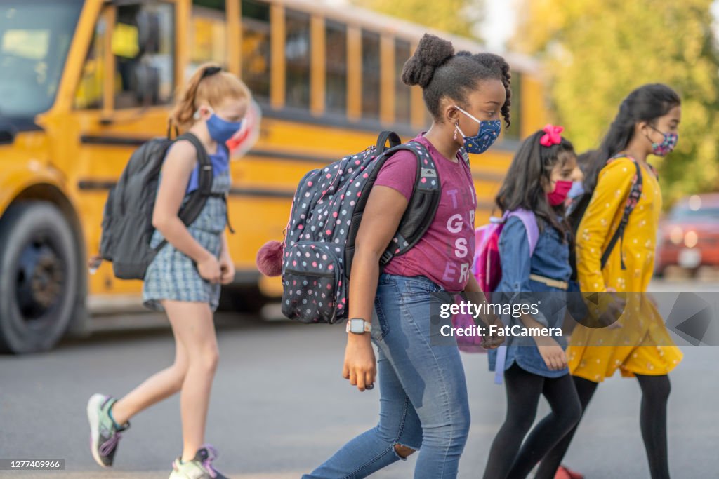 Multi-ethnic group of students crossing the road after getting off the bus