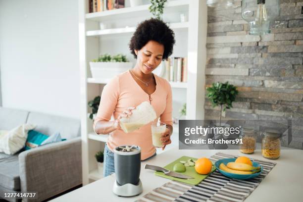 gelukkige afrikaanse amerikaanse vrouw die een voedingsontbijt thuis voorbereidt - nutritional supplement stockfoto's en -beelden