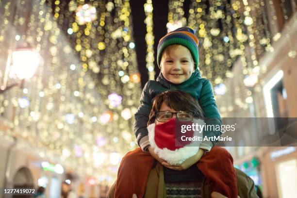 familie genießt weihnachtsbeleuchtung in einer stadtstraße während covid-19 pandemie - coronavirus winter stock-fotos und bilder