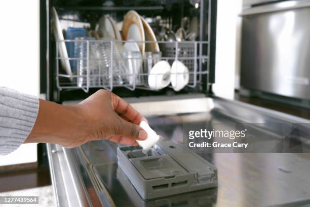 woman puts dishwasher detergent into dispenser - dishwasher stock pictures, royalty-free photos & images