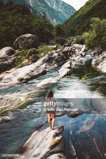 mujer viajera de pie en una roca con vistas al río en el valle de verzasca - valle fotografías e imágenes de stock
