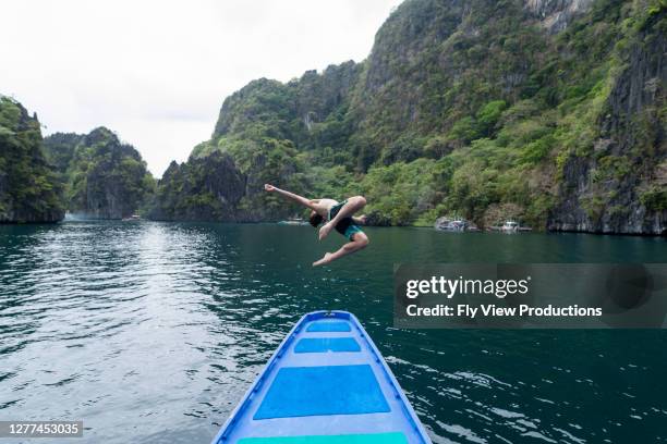 young adult man does back flip off the bow of a boat in the philippines - somersault stock pictures, royalty-free photos & images