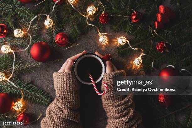 woman holding in hands hot christmas tea with candy cane against decorations, gift boxes, ribbon and ginger bread on wooden board. xmas concept. eye bird view. - chocolate top view imagens e fotografias de stock