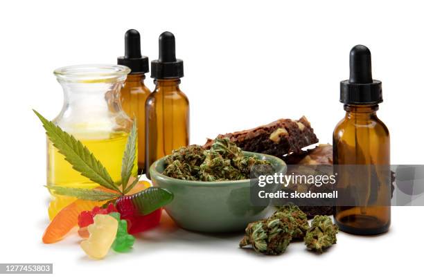 de oliën en de knop van de cannabis in een kleine kom die door zoete edibles wordt omringd - cannabis narcotic stockfoto's en -beelden