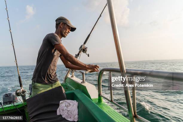 fisherman preparing the fishing equipment, attaching a bait aboard a boat during the deep sea fishing in the ocean. - daily life traditional fishermen stock pictures, royalty-free photos & images