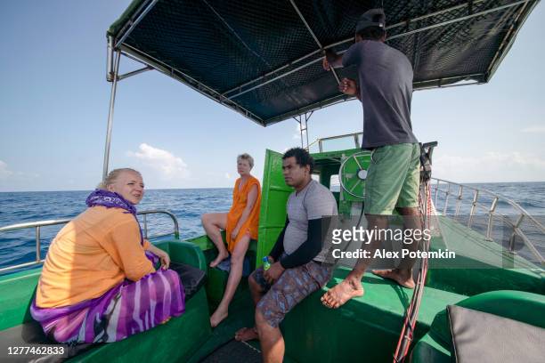 tourists, european women, are resting under the tent and talking with a local guide and the captain at the back of the fishing boat during the deep sea fishing trip in the indian ocean, at the sri lanka coast. - shade45 stock pictures, royalty-free photos & images