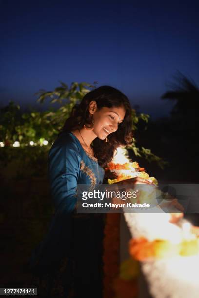 woman lighting oil lamps around house celebrating diwali festival - diwali lights stock-fotos und bilder