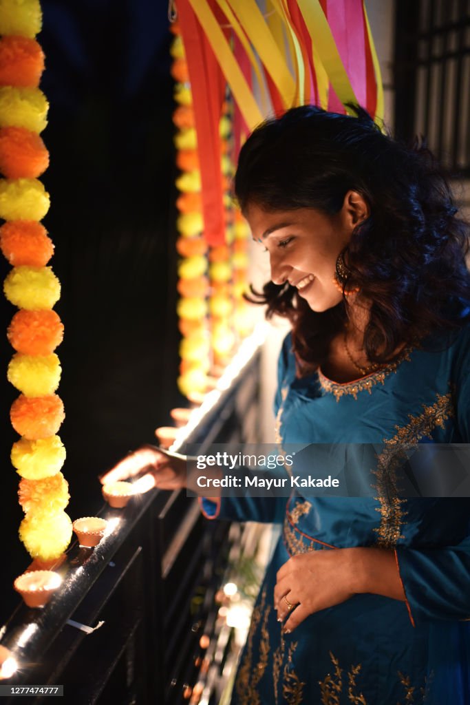 Woman lighting oil lamps around house celebrating Diwali festival