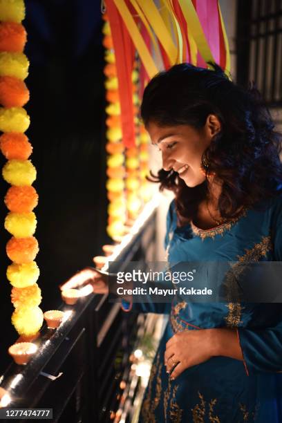 woman lighting oil lamps around house celebrating diwali festival - diwali festival of lights stock pictures, royalty-free photos & images