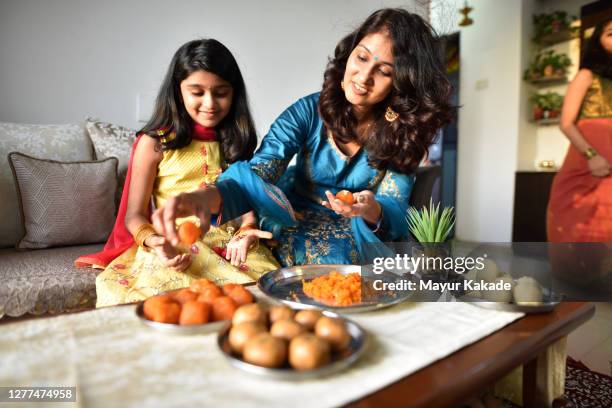 mother and daughter making indian sweet laddoos for the traditional festival - diwali sweets stock pictures, royalty-free photos & images