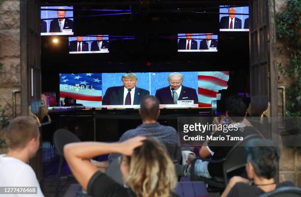People sit and watch a broadcast of the first debate between President Donald Trump and Democratic presidential nominee Joe Biden at The Abbey, with...