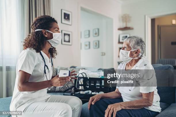 female doctor during a home visit during the covid-19 pandemic - ponto de verificação de temperatura imagens e fotografias de stock