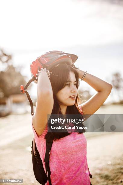 portrait of young female putting on her bike helmet - teenager cycling helmet stock pictures, royalty-free photos & images