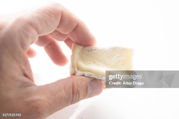 man with a slice of soft cheese in hand. - brie stock pictures, royalty-free photos & images