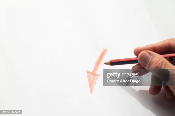 a man draws a descending arrow on a white paper: sales are down, crisis. - hand drawn arrow stock-fotos und bilder