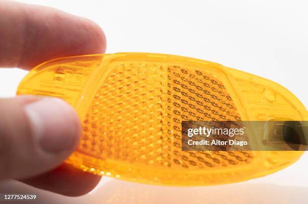 a person holds an orange reflector for a bicycle in his hand. - reflector objeto fabricado fotografías e imágenes de stock