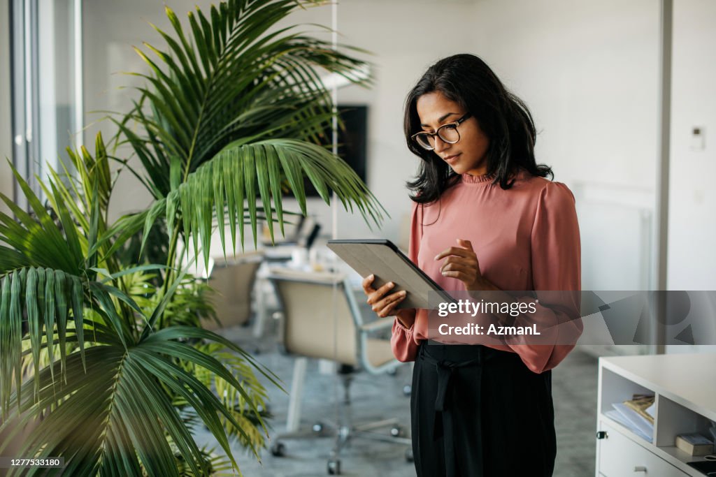 Jeune femme d’affaires indienne utilisant la tablette numérique dans le bureau