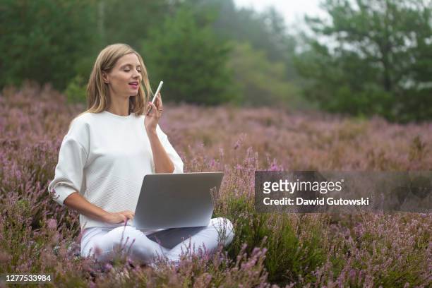 woman working with laptop and phone with speech recognition - flexible work stock-fotos und bilder