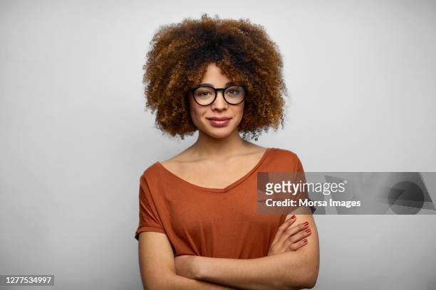 smiling young female afro owner against white background - eine frau allein stock-fotos und bilder