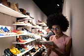 Young woman using digital tablet to check invetory at a shoe store
