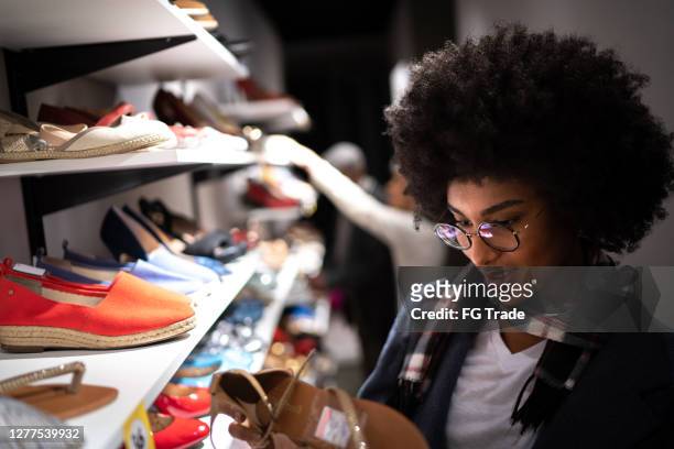 jeune femme faisant du shopping pour des chaussures - magasin de chaussures photos et images de collection