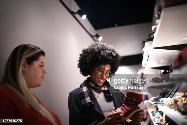 young woman being helped by a saleswoman while shopping for shoes in a thrift store - shoe shop assistant stock pictures, royalty-free photos & images