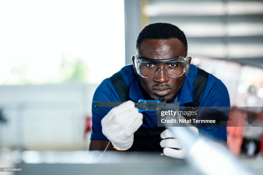 Quality Control Engineer measuring a mechanical material part production by digital calipers in warehouse factory shop floor. Quality Control Assurance.