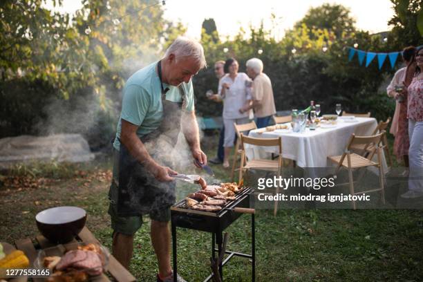 senior mann macht grill ensto,für seine freunde während der party im hinterhof - barbeque party woman stock-fotos und bilder