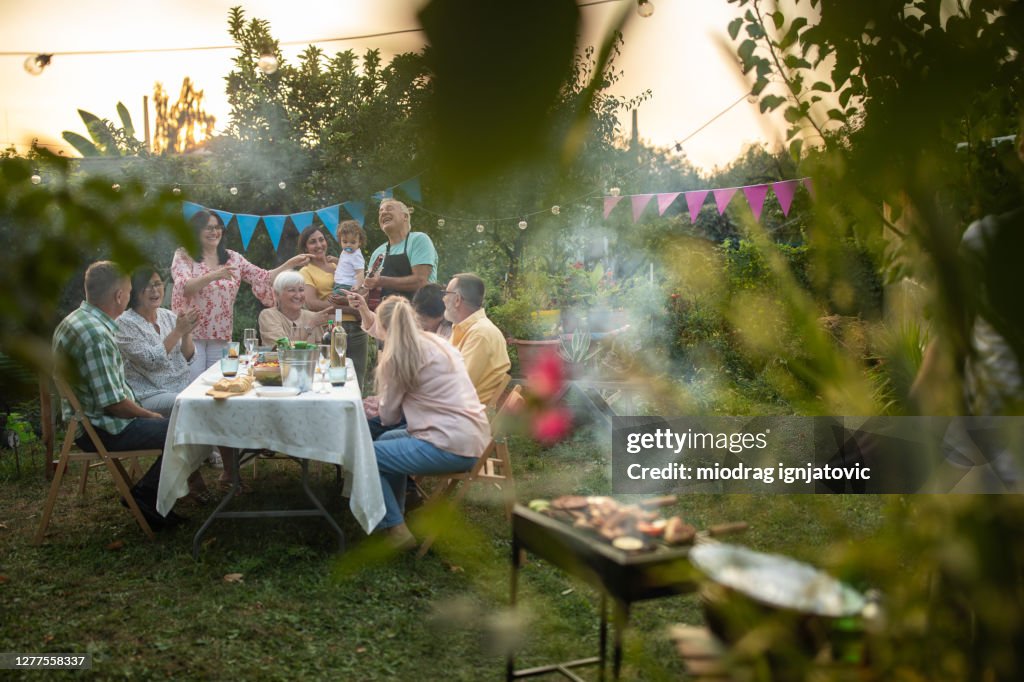 Mehrgenerationenfamilie und Freunde feiern Geburtstag der Großmutter im Hinterhof während des schönen Sommertages