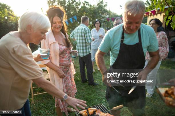 senior mann macht grill ensto,für seine freunde während der party im hinterhof - barbeque party woman stock-fotos und bilder