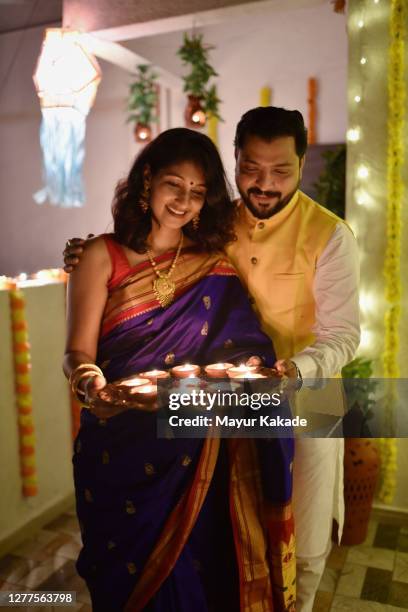 portrait of a couple holding oil lamps on diwali festival - diya oil lamp fotografías e imágenes de stock