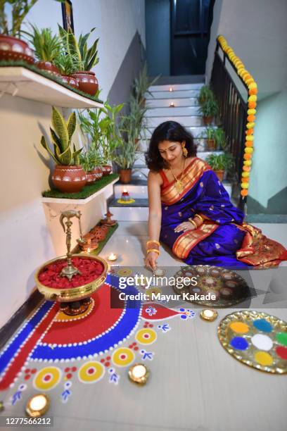 indian woman dressed in traditional wear decorating house with oil lamps - diya oil lamp fotografías e imágenes de stock