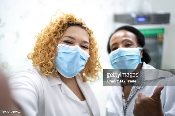 happy healthcare coworkers taking a selfie at hospital - protective face mask happy stock pictures, royalty-free photos & images