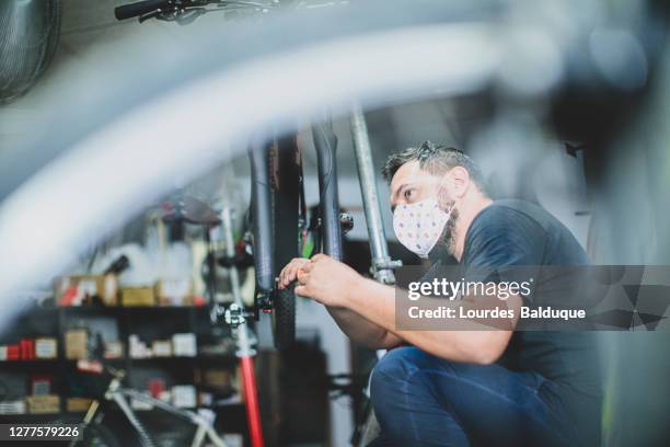 a man with face mask in his bike rental and repair shop - castellon province stock pictures, royalty-free photos & images