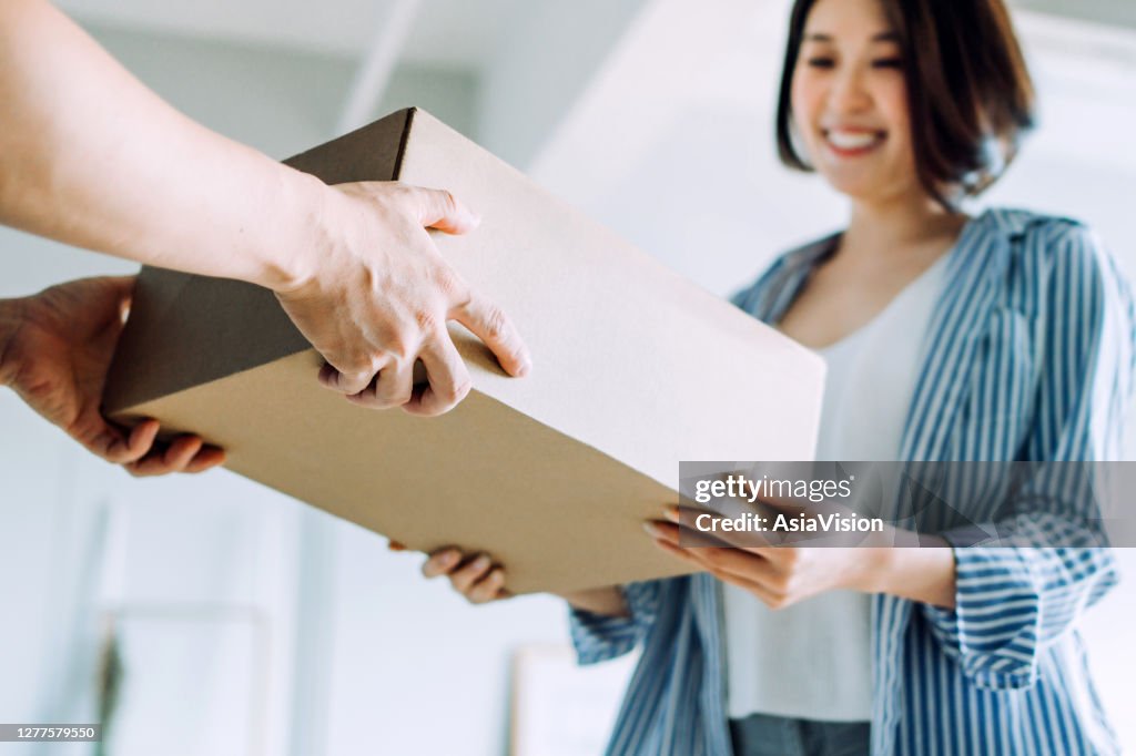 Nahaufnahme einer Kurierperson, die eine Lieferung an einen Kunden zu Hause macht. Bereitstellung einer schnellen Express-Lieferung direkt in die Hände des Kunden