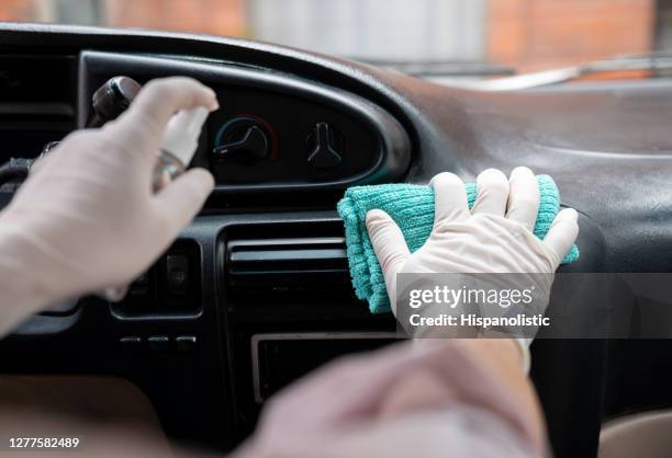 close-up on a man disinfecting the dashboard of his car during the covid-19 pandemic - biosecurity stock pictures, royalty-free photos & images