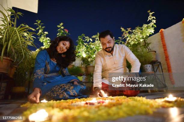 indian couple in traditional wear decoration petal rangoli with oil lamps - ganesh chaturthi fotografías e imágenes de stock