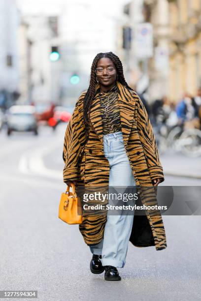 Influencer Lois Opoku, wearing a tiger colored coat with tiger pattern by Lala Berlin, a tiger colored shirt with tiger pattern by Lala Berlin, a...