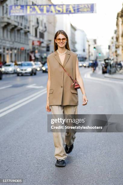 Influencer Jacqueline Zelwis, wearing a beige vest by Munthe, beige pants by Holzweiler, black sneakers by Balenciaga, a brown bag by Boyy and...