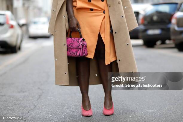 Influencer Lois Opoku, wearing a purple colored top and a orange colored skirt by Dorothee Schumacher, a beige coat with ponted cutouts by Lala...