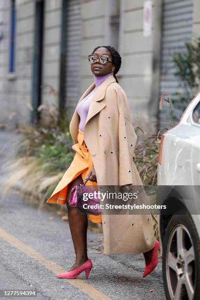 Influencer Lois Opoku, wearing a purple colored top and a orange colored skirt by Dorothee Schumacher, a beige coat with ponted cutouts by Lala...