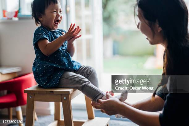 young mother helping daughter to put on socks - toddler laughing stock pictures, royalty-free photos & images