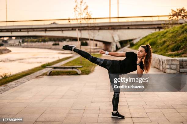 young sporty woman doing high kick outdoors - high kick stock pictures, royalty-free photos & images