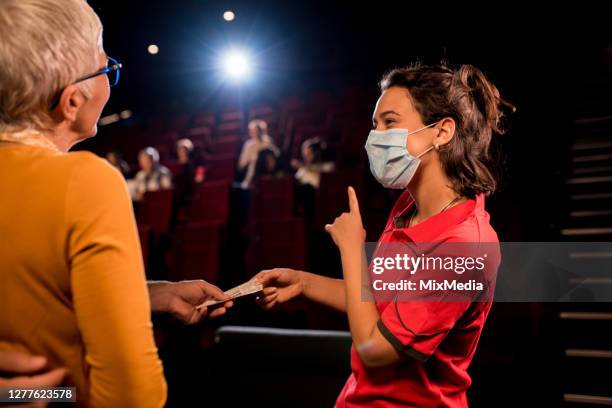 young cinema worker checking the tickets and guiding spectators to their seats - video reviewed stock pictures, royalty-free photos & images